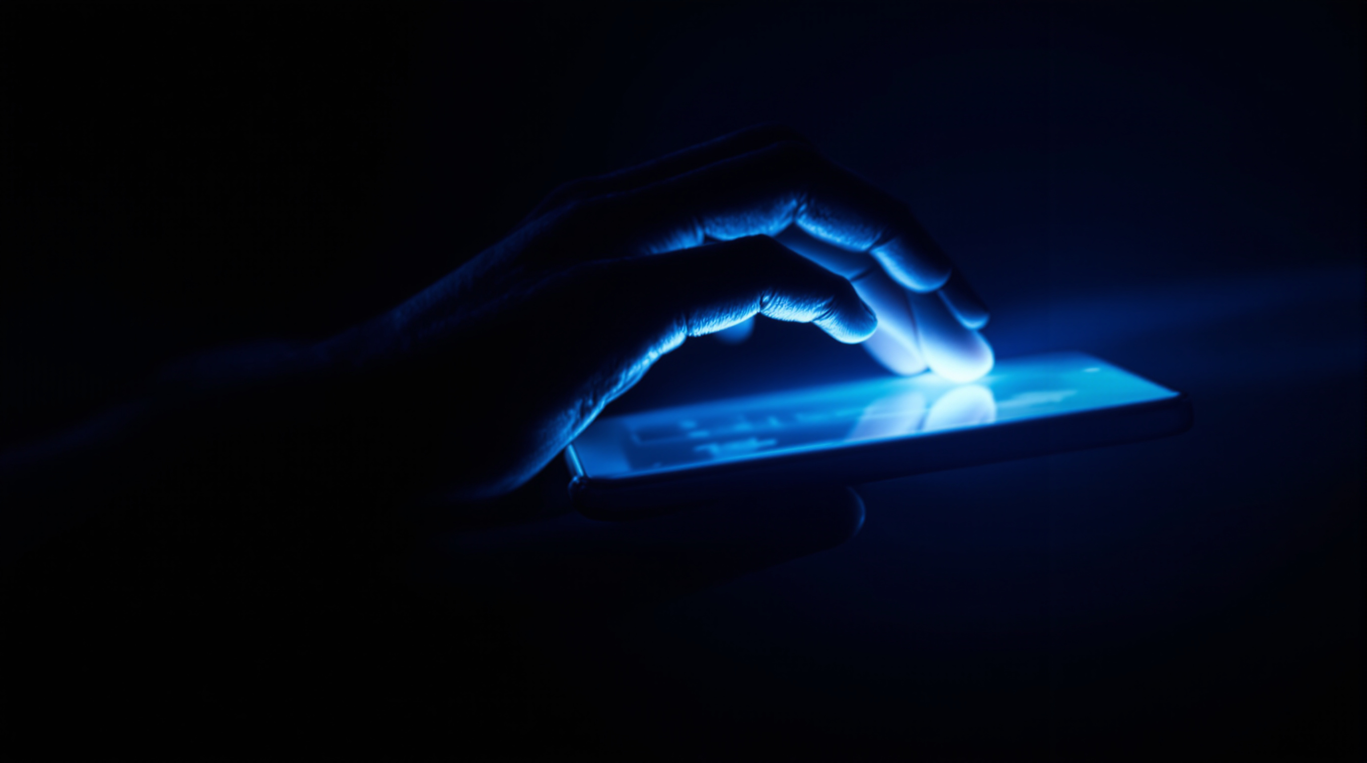 Main attirée par l'écran lumineux d'un téléphone dans l'obscurité, image de la cyberdépendance